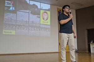 Jose JR vestindo camisa escura , calça bege segurando microfone no palco principal do Festival DevPira 2023 sendo Keynnote de encerramento.